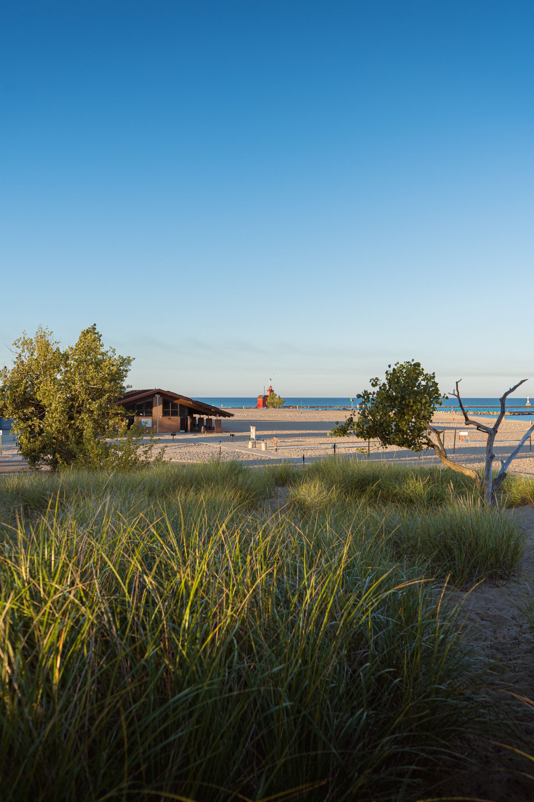 A peaceful beach view with Big Red Lighthouse in Holland, Michigan, backed by blue skies.
